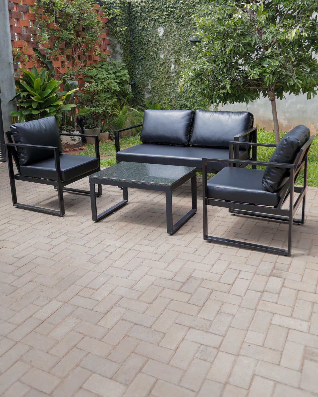 Juego de living Aura en negro, completo, en un patio con plantas